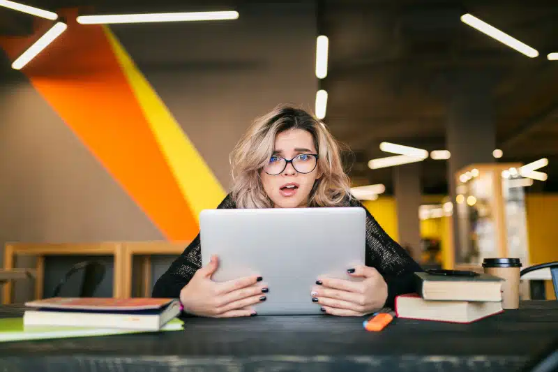 portrait of a young woman socked faced expression holding a laptop