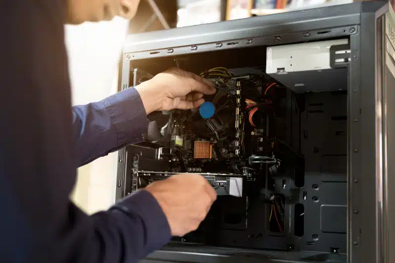 Technician with a screwdriver fixing a computer.