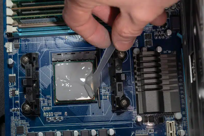 Applying thermal paste with spatula in CPU on motherboard. 