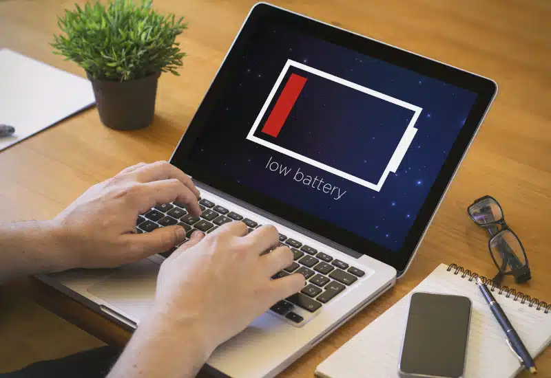 Close-up top view of man working on laptop with low battery. 